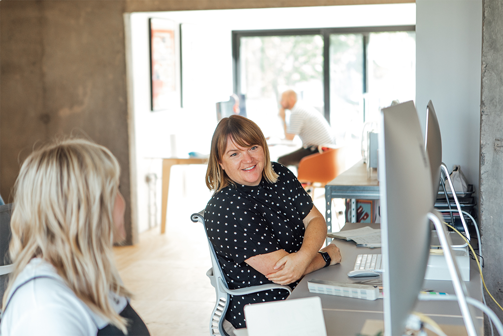 Woman with spotty black shirt looking at a silver computer monitor